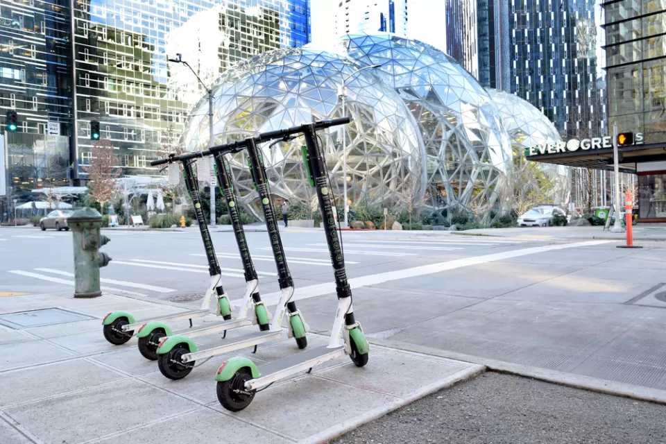 A row of Electric Scooter for sharing from Lime in Seattle with the Amazon Spheres in the background.